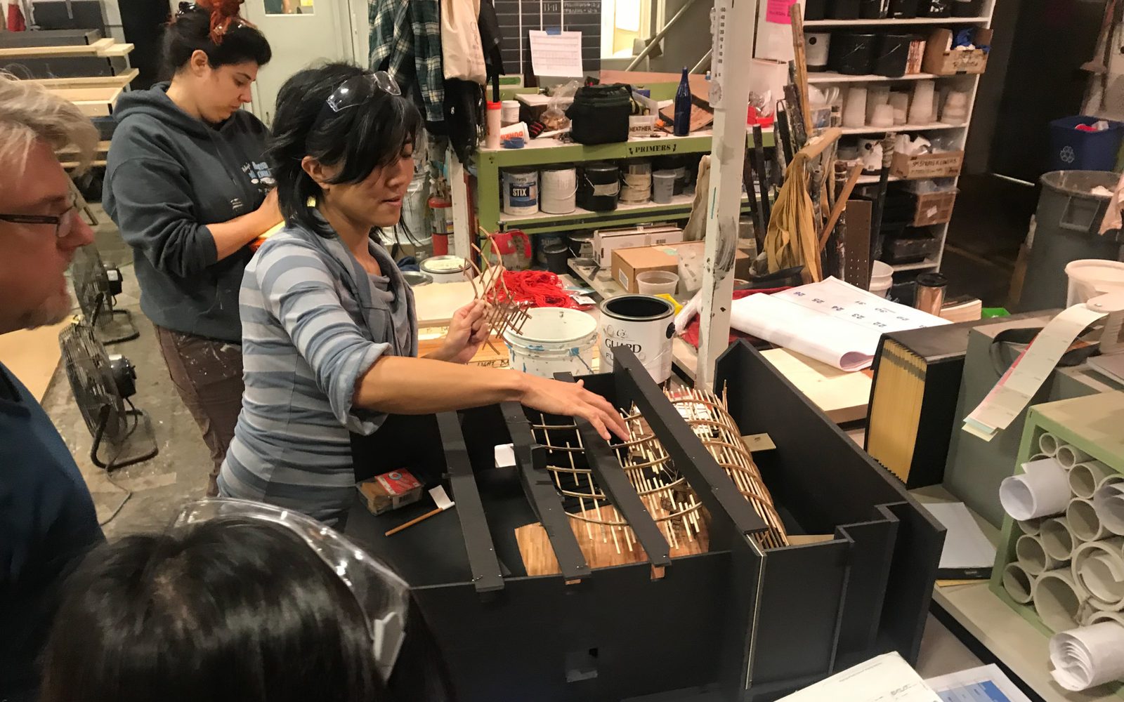 Scenic Designer Mimi Lien discussing the Moby-Dick set model with artisans at the A.R.T. Scene Shop.
