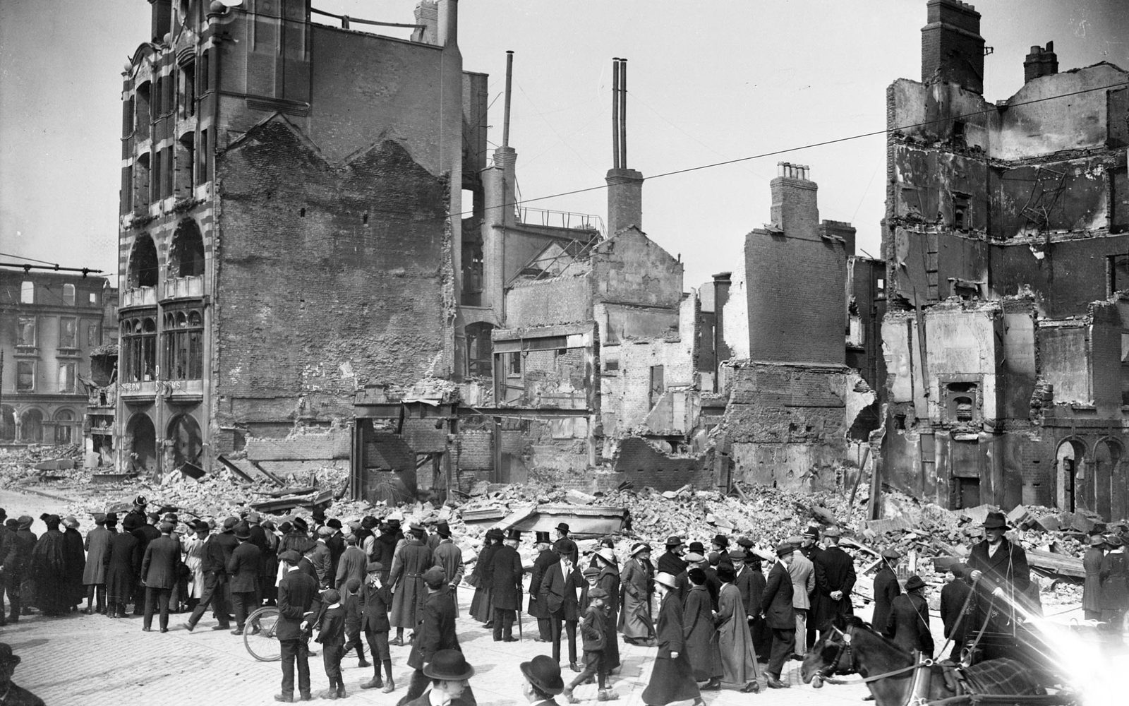 A crowd gathers around the ruins of the Dublin Bread Company building.