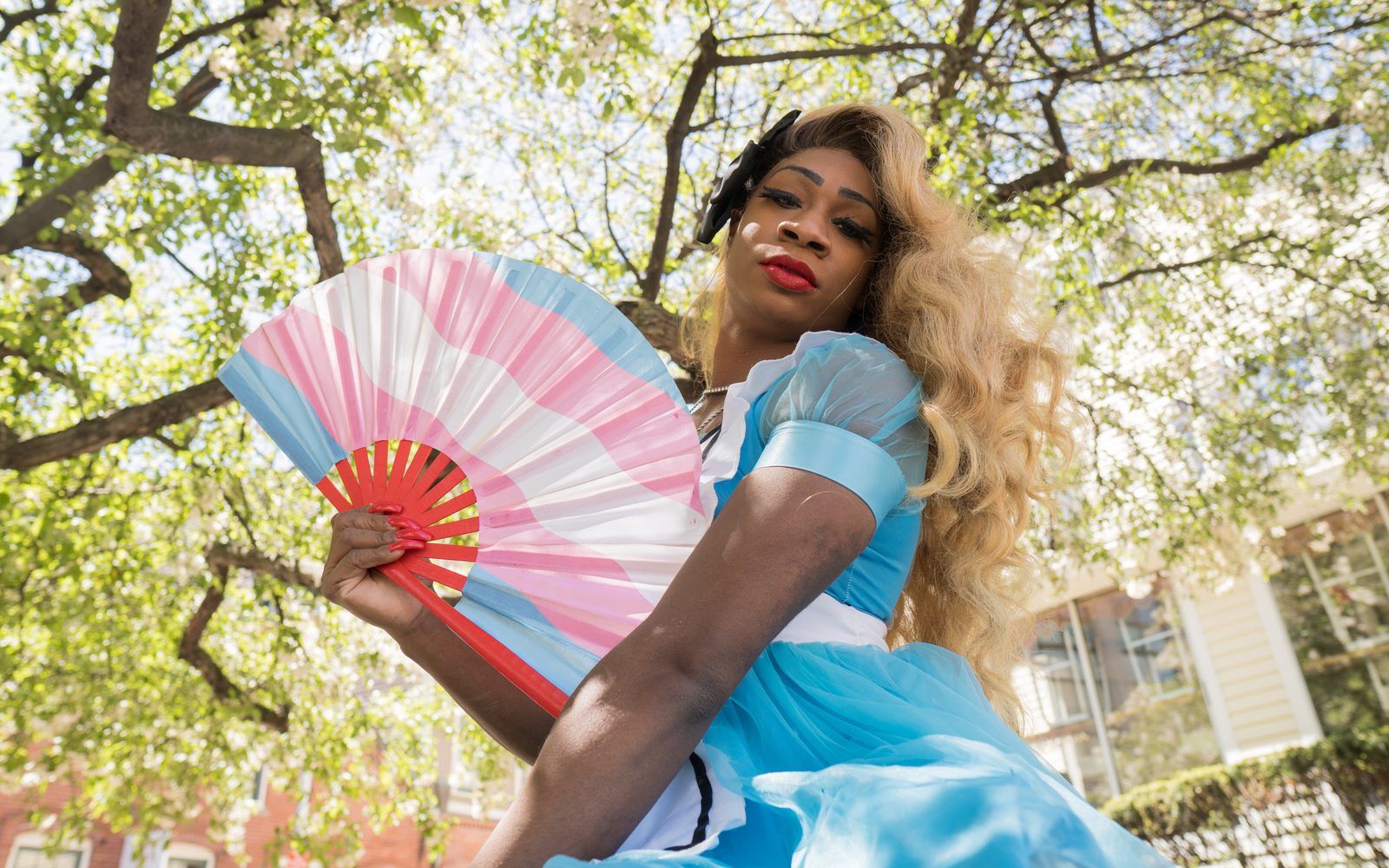 Lilly Rose Valore as Alice with a transgender pride-themed hand fan.