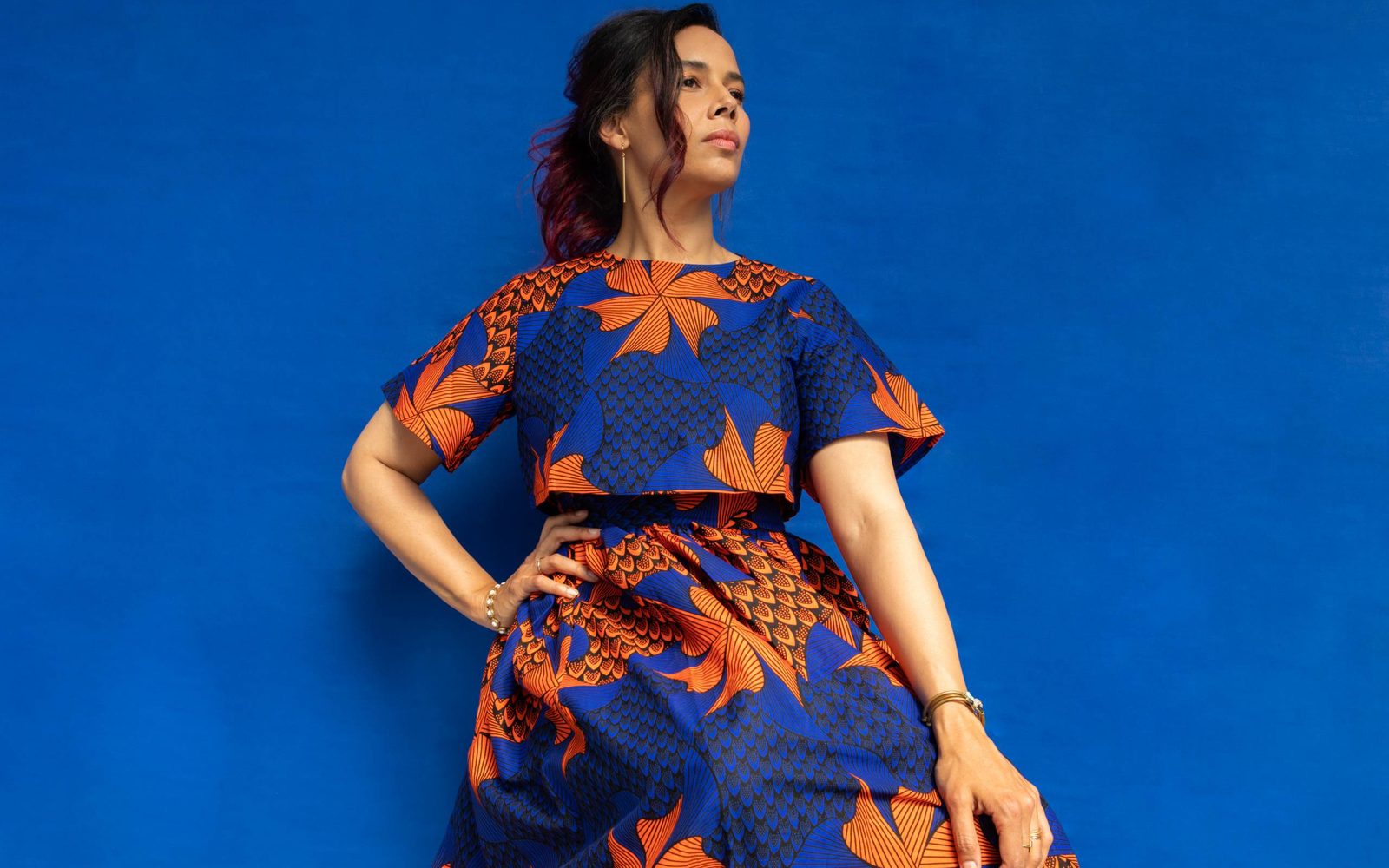 Rhiannon Giddens in a wax print two piece in front of a blue backdrop.