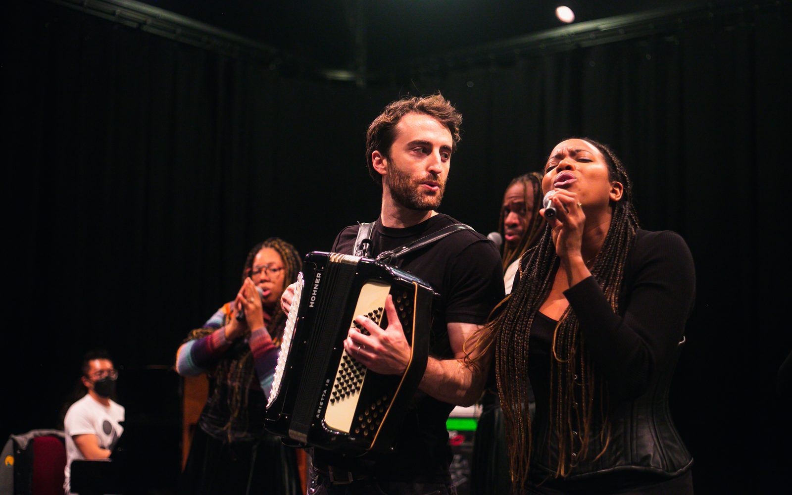 Steven Cuevas at the piano with Kira Helper singin, Charlie Thurston on accordion, Reggie D. White singing, and Whitney White singing.