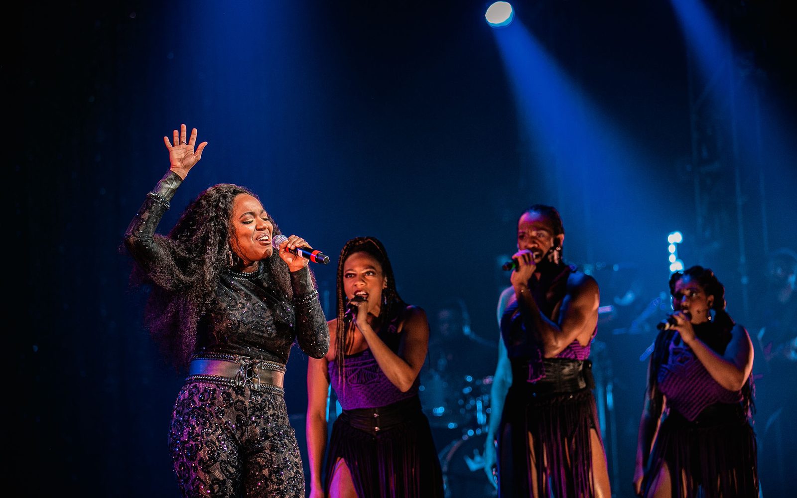 Whitney White raising her hand singing while Phoenix Best, Reggie D. White, and Kira Sarai Helper sing behind her.