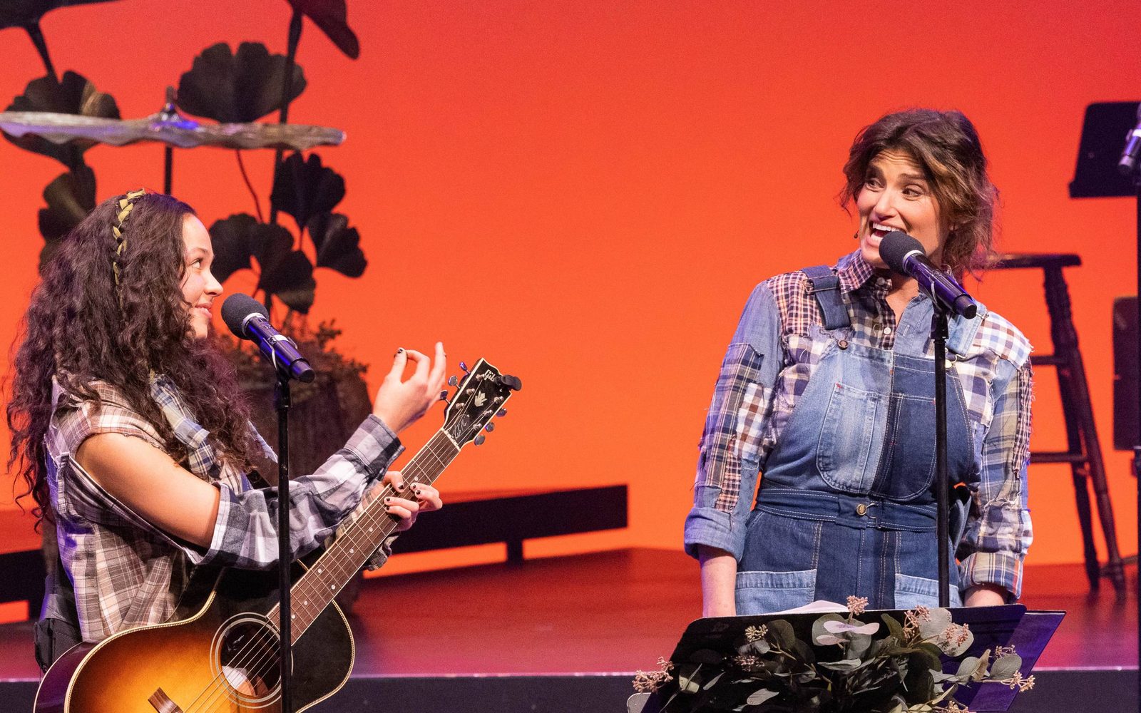 YDE with guitar looking at and Idina Menzel singing in WILD: A Musical Becoming.