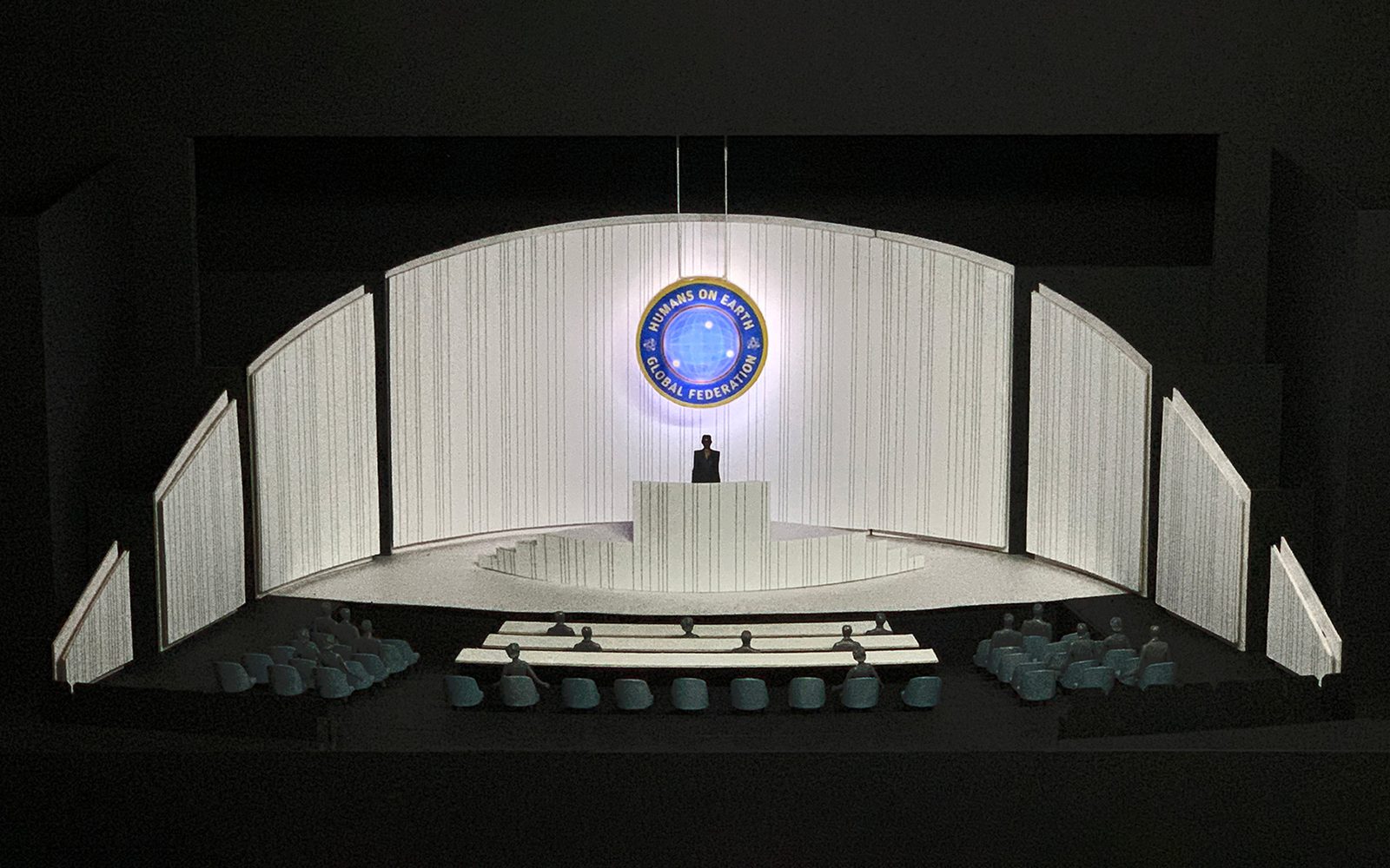A model of the Ocean Filibuster set: a patterned white stage with a podium against a black background.