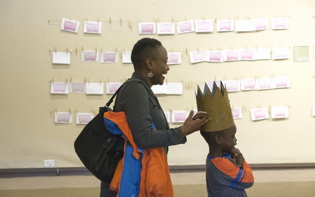 A woman places a paper crown on a child's head.