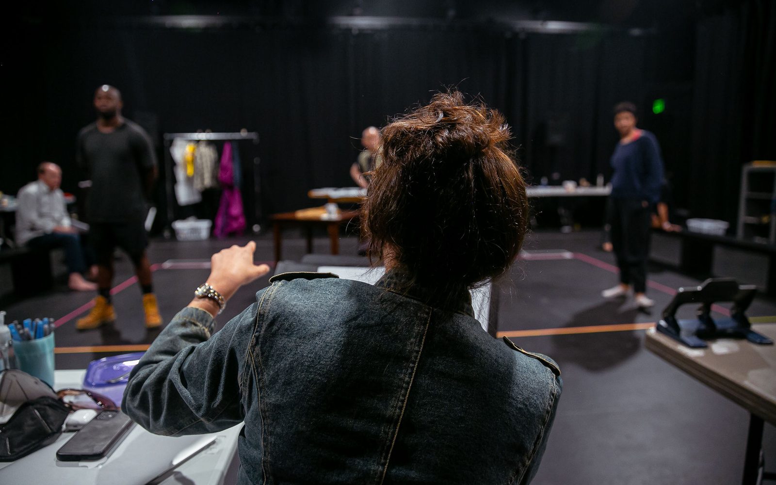 The back of Director Taibi Magar as she works with the actors in rehearsal.