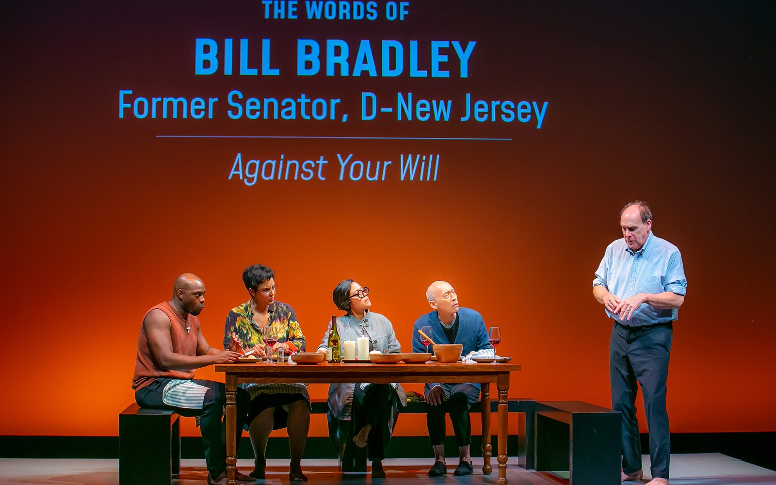 Wesley T. Jones, Tiffany Rachelle Stewart, Elena Hurst, and Francis Jue sit around a table as Carl Palmer stands to the right, in front of a wall that says, “The Words of Bill Bradley, Former Senator, D-New Jersey: ‘Against Your Will’”.