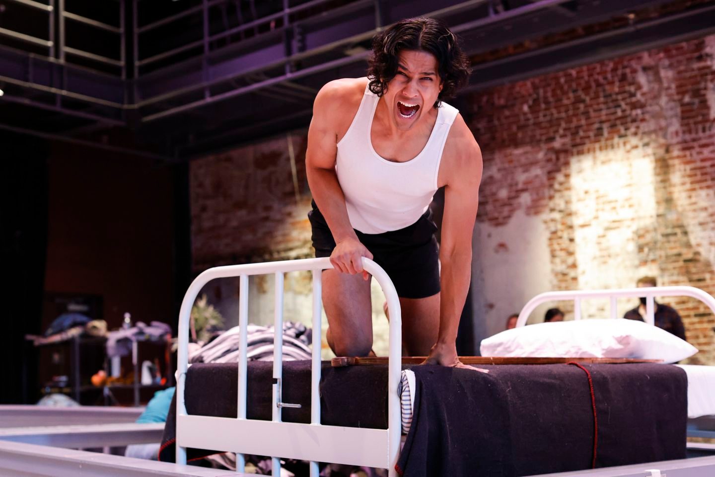 Adi Dixit yells while leaning over a metal bed.