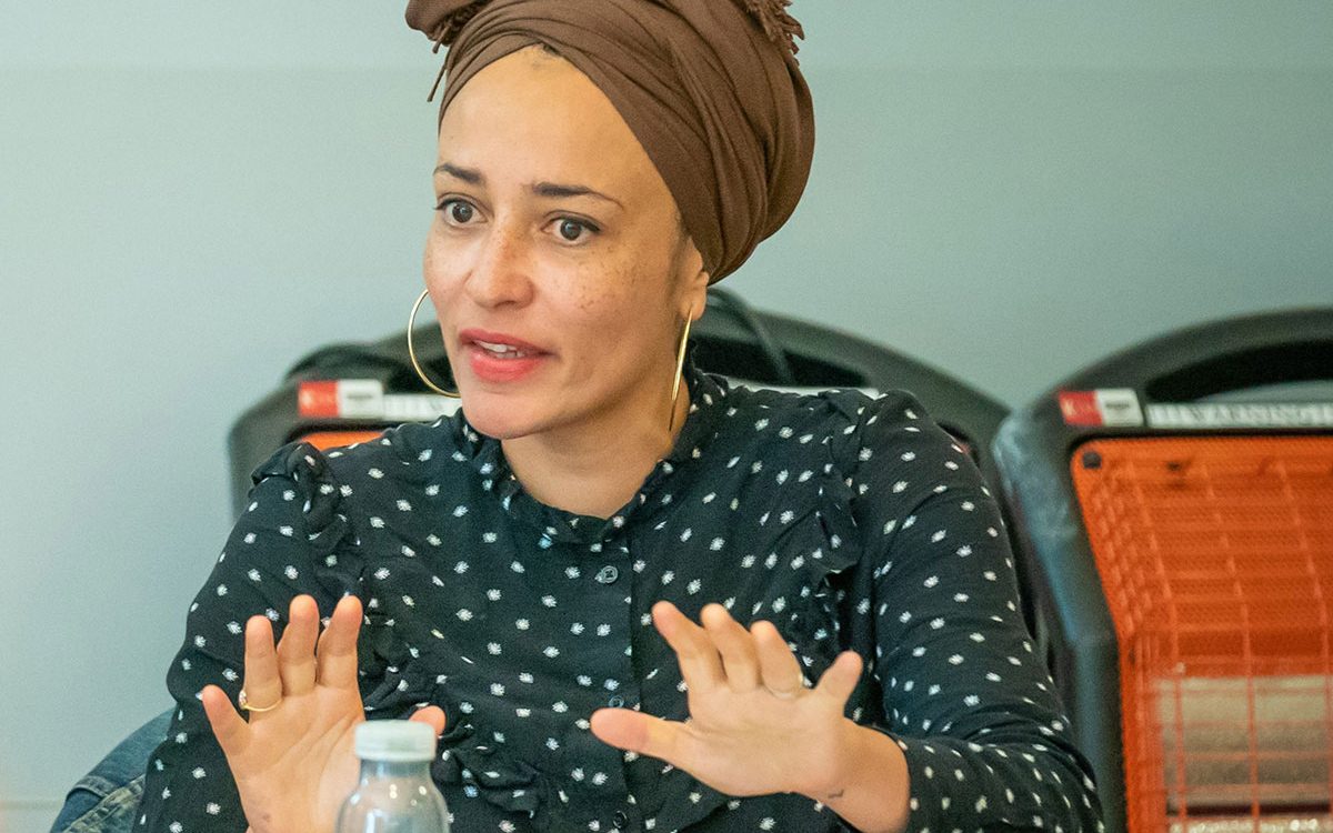 Zadie Smith in a polka dot blouse and brown head-wrap talking while seated.