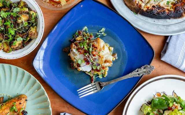 A blue plate of food surrounded by other white plates of food.