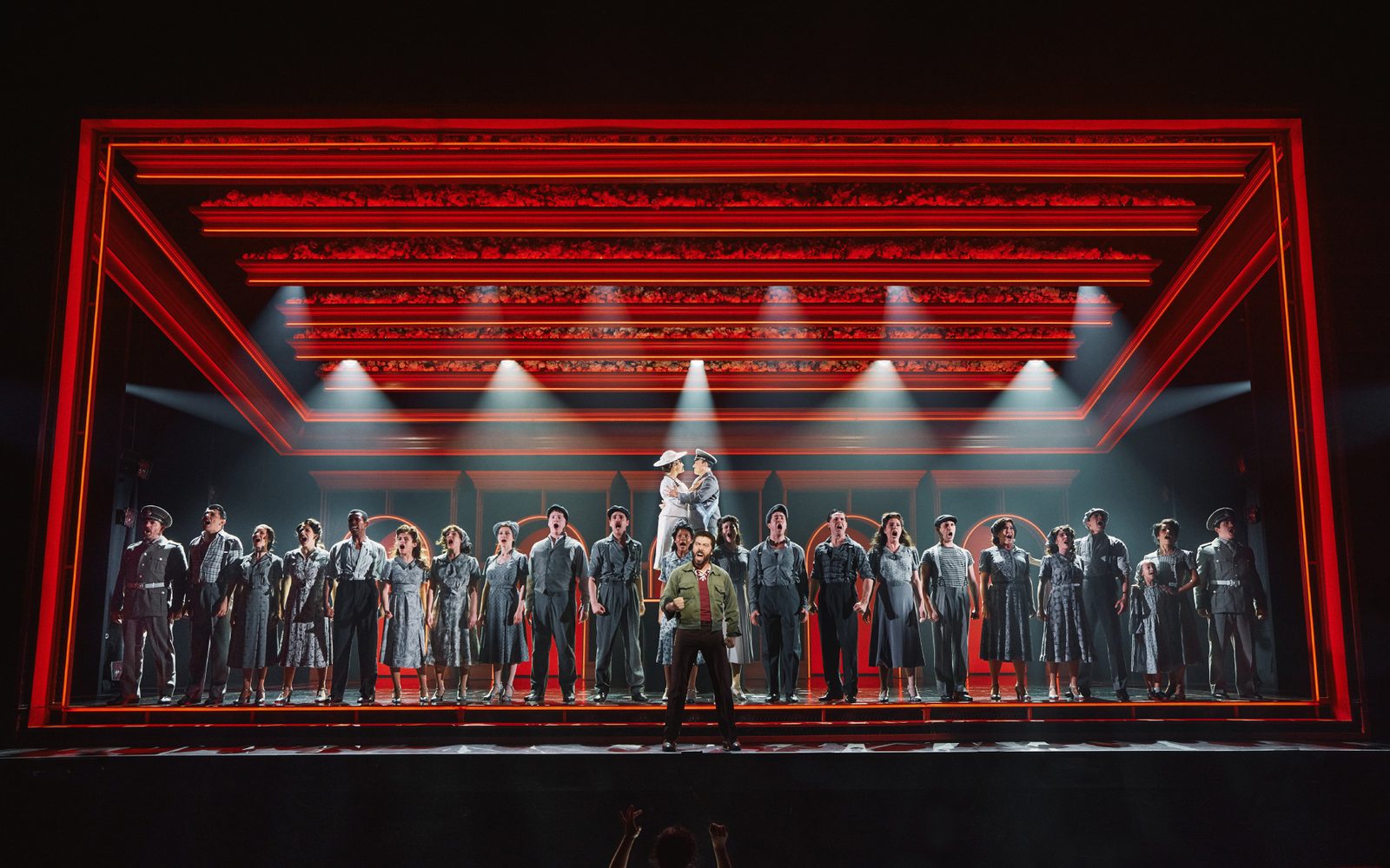 The company of Evita sings on stage.