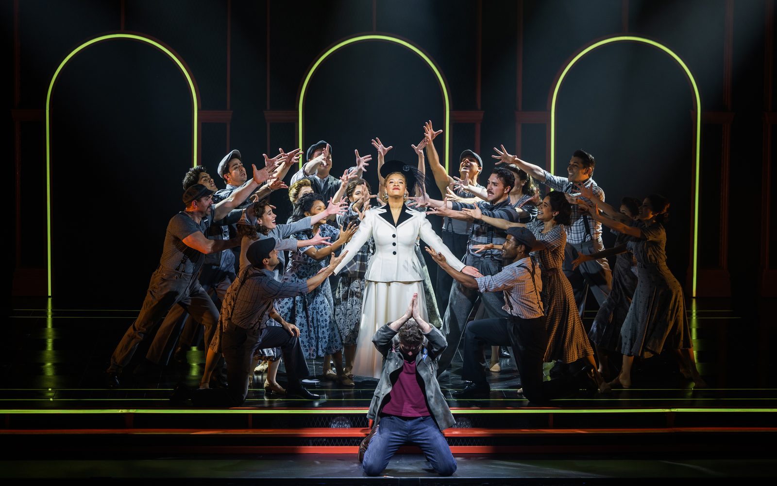 The company of Evita poses around Shereen Pimentel (Eva), gesturing towards her dramatically.