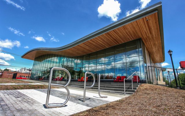 A view of the East Boston Branch Library with a bike rack shaped like the letters B-P-L in front.