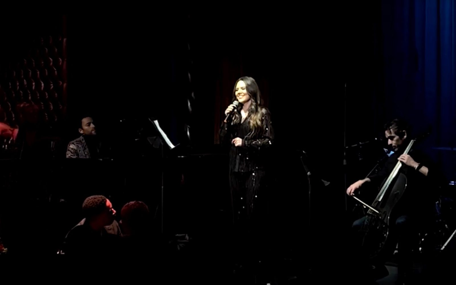 Joy Huerta sings into a microphone with Benjamin Velez at the piano.