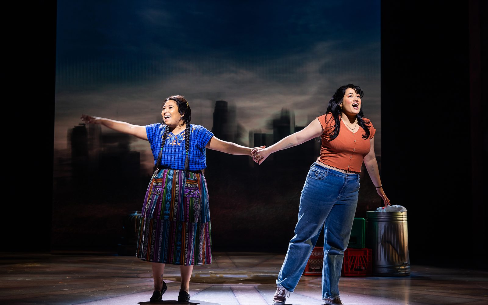 Satya Chávez and Lucy Godínez singing while holding hands.