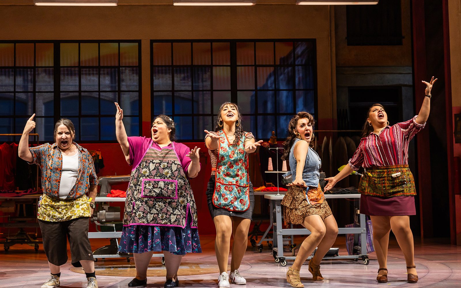 Sandra Valls, Carla Jimenez, Shelby Acosta, Jennifer Sánchez, and Florencia Cuenca strike a pose in their sewing uniforms in the garment factory.