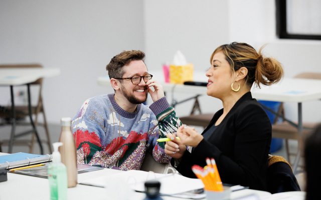 Petey Gibson and Elena Hurst chat while sitting at a table.