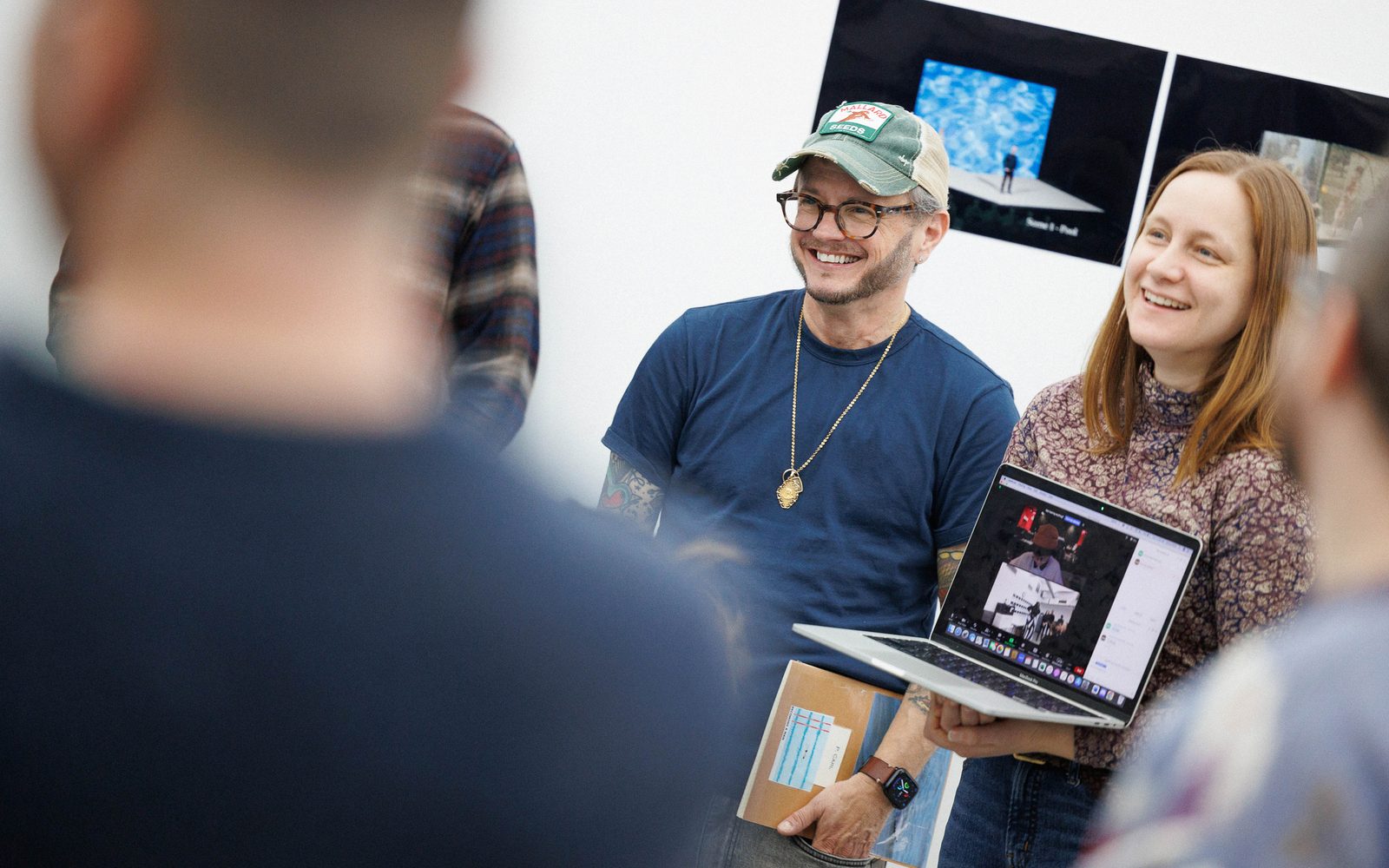 P. Carl stands next to Emma Watt, who holds a computer open to Zoom.