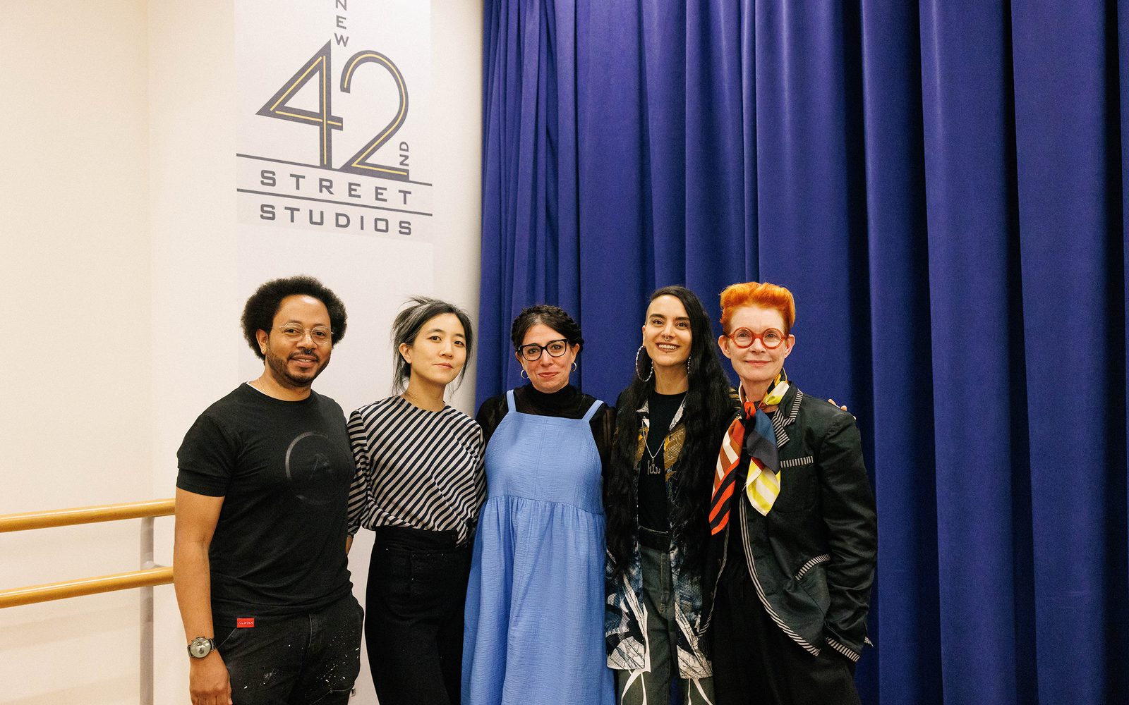 Alan C. Edwards in a black graphic tee, Mimi Lien in a black-and-white diagonally striped blouse, Rahcel Chavkin in a blue dress and black top, Sonya Tayeh in a colorful jacket and black shirt, and Sandy Powell in a black jacket and colorful scarf pose for the camera.