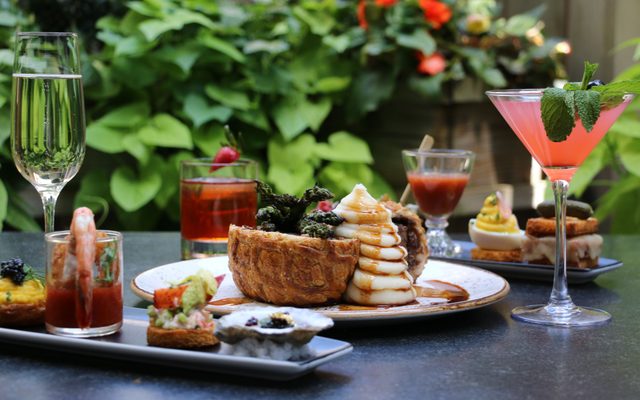 A flute of champagne and a cocktail in a martini glass flank a split beef wellington with with mashed potatoes cascading off it.