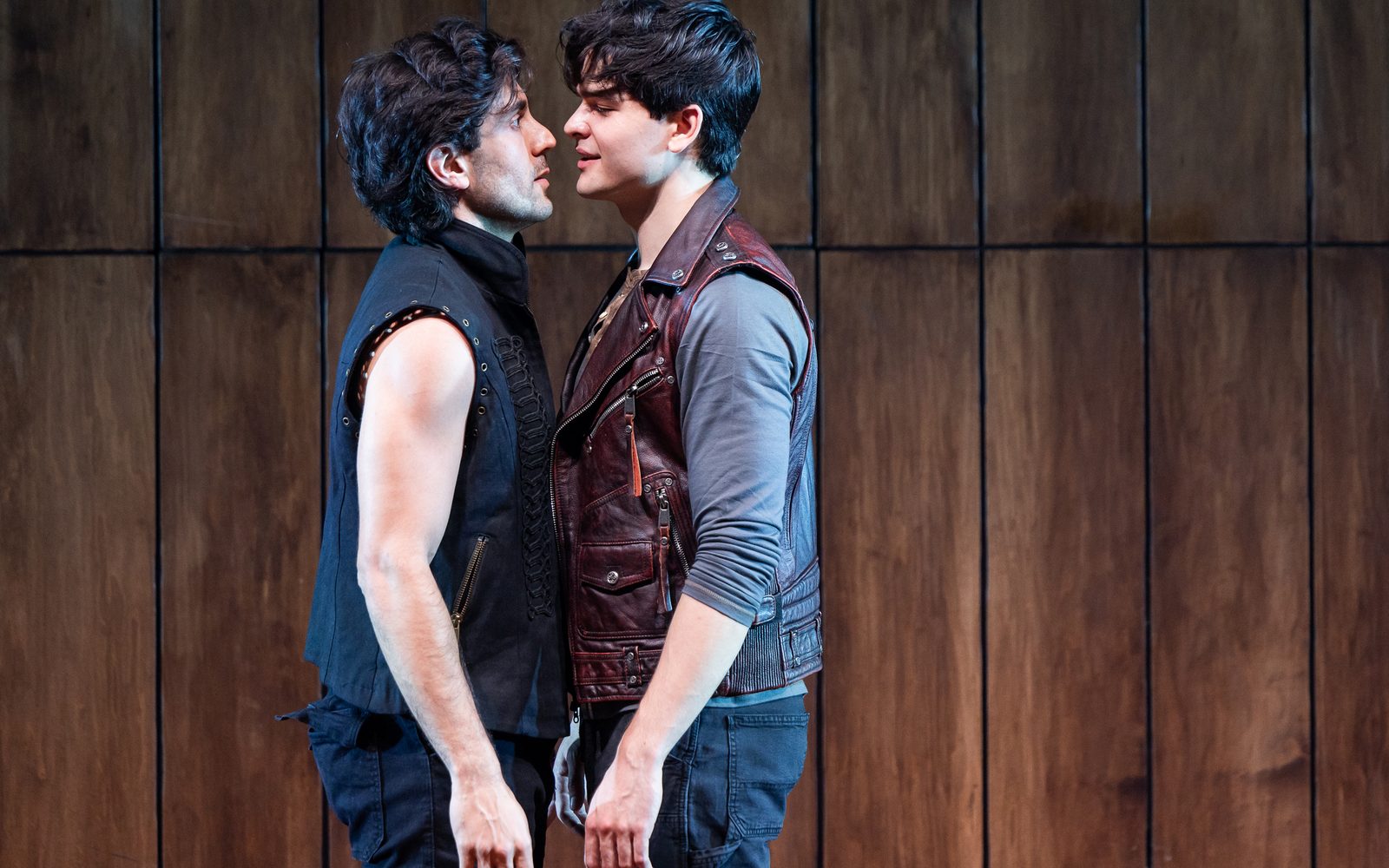 Adam Shaukat in a black vest and Will Savarese in a leather vest get close to one another staring into the others’ eyes intimidatingly.