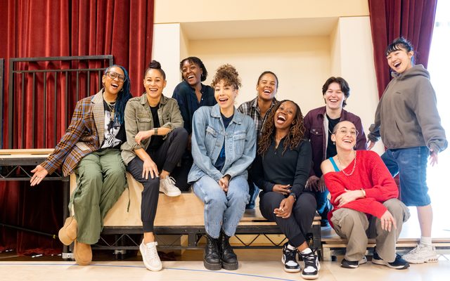 A group shot of the cast and the director arranged in two rows.
