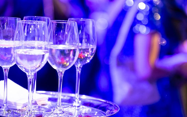 A tray of wine glasses bathed in purple light.