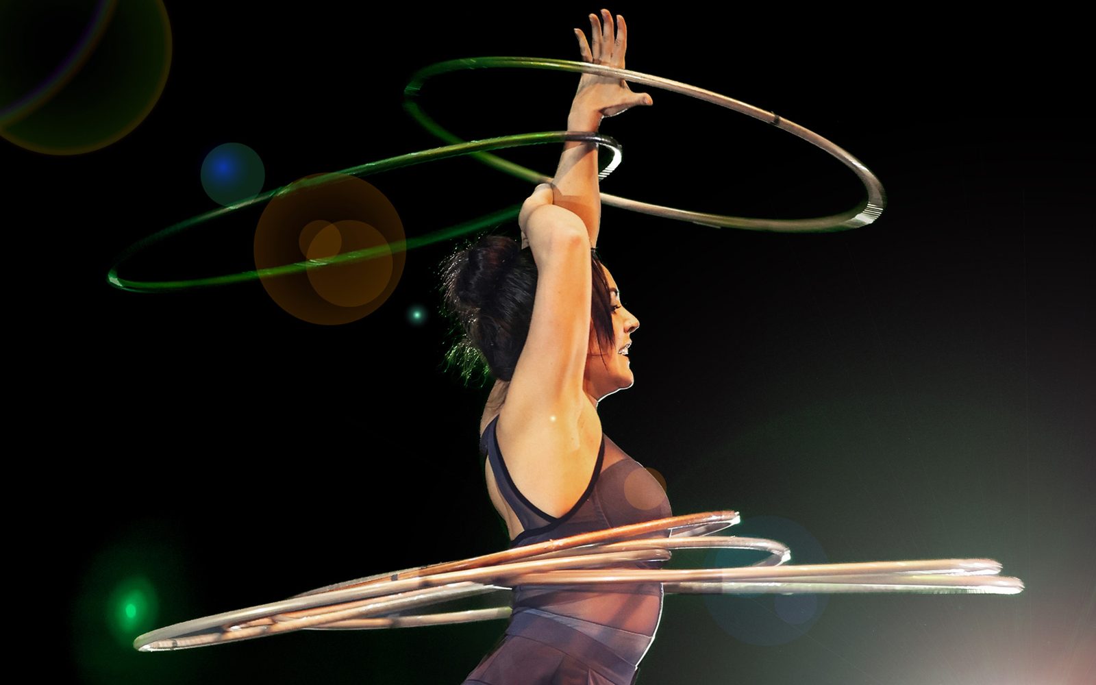 Méliejade Tremblay-Bouchard swings two hula hoops around her raised arms and four more around her waist.