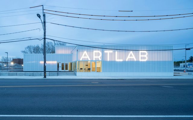 Exterior elevational view of the building at dusk with the lighted sign that says, “ArtLab”.