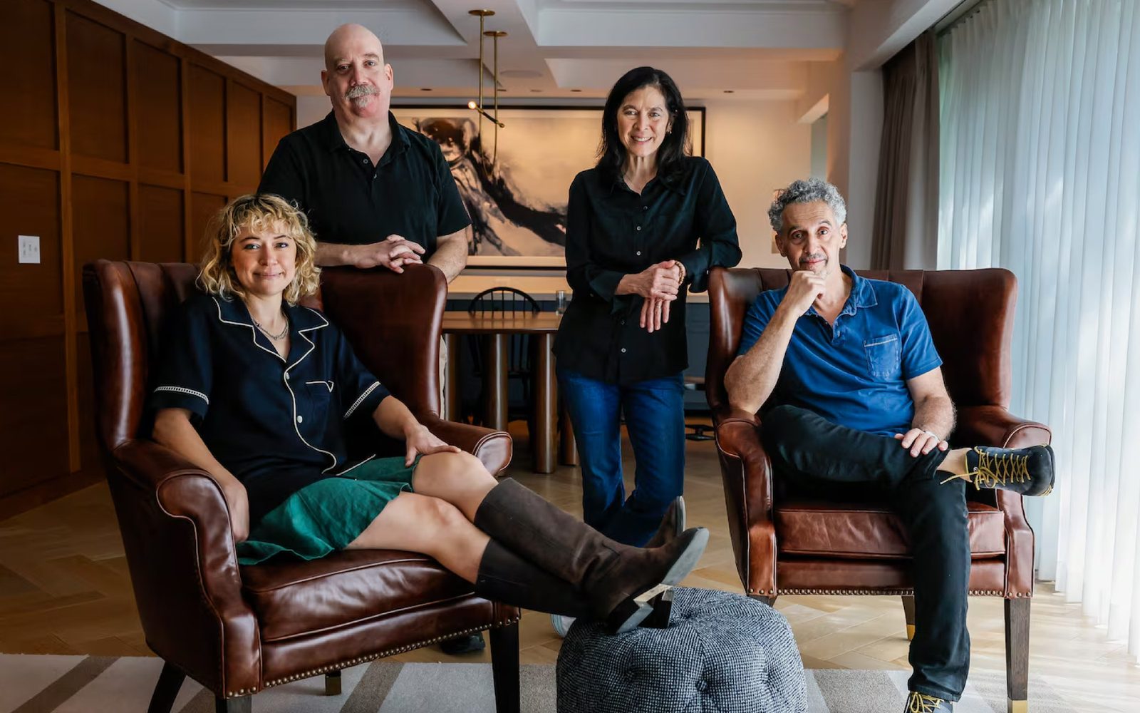 Tatiana Maslany and John Turturro sit comfortably in wingback leather arm chairs, while Paul Giamatti and Diane Paulus stand leaning casually on the chairs.