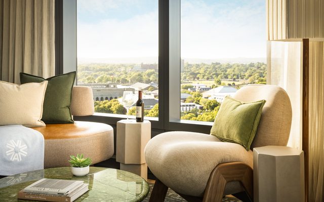 Comfy, earth-toned seating in a room, with a view of the Harvard Business School through a large window.